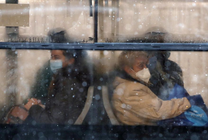 People wearing a face mask to protect against coronavirus sit on a bus in Belgrade, Serbia, Monday, Jan. 11, 2021. A spate of rainy and snowy weather across the Balkans in the past days has left homes and fields flooded, disrupted road and sea traffic and caused power outages. (AP Photo/Darko Vojinovic)