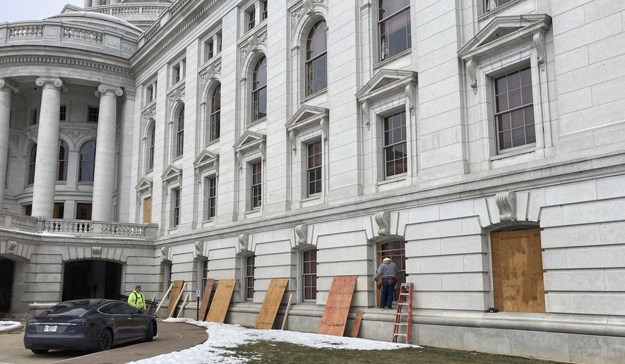 Workers begin boarding up the Wisconsin state Capitol building in Madison on Monday, Jan. 11, 2021. State officials are concerned about the prospects of state-centered violence in the wake of last week&#39;s security breaches at the U.S. Capitol. (AP Photo/Todd Richmond)