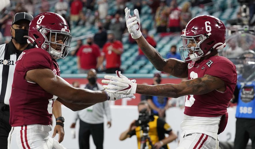 Alabama wide receiver John Metchie III, left, congratulates wide receiver DeVonta Smith, after Smith scored a touchdown against Ohio State during the first half of an NCAA College Football Playoff national championship game, Monday, Jan. 11, 2021, in Miami Gardens, Fla. (AP Photo/Chris O&#x27;Meara)