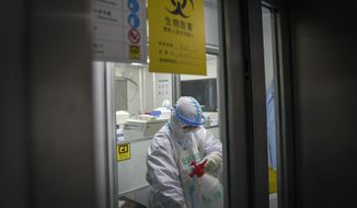In this photo released by Xinhua News Agency, a medical worker disinfectants herself at a testing lab of KingMed Diagnostics Group Co., Ltd. in Shijiazhuang in northern China&#39;s Hebei Province on Saturday, Jan. 9, 2021. (Mu Yu/Xinhua via AP) ** FILE **