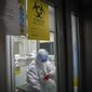 In this photo released by Xinhua News Agency, a medical worker disinfectants herself at a testing lab of KingMed Diagnostics Group Co., Ltd. in Shijiazhuang in northern China&#39;s Hebei Province on Saturday, Jan. 9, 2021. (Mu Yu/Xinhua via AP) ** FILE **