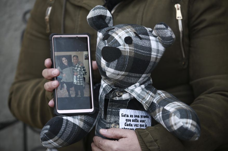 Araceli Ramirez shows a stuffed bear she had made from the shirt of her father, Lorenzo Ramirez, who died so quickly from COVID-19 two months ago that she was unable to say goodbye, as she stands outside the home of bear maker Erendira Guerrero following a TV interview, in Ciudad Juarez, Mexico, Monday, Jan. 11, 2021. Ramirez, who had the bear made from a warm winter shirt her father loved, said "I can talk to the bear, express what I didn't tell him, and feel like he is with me." (AP Photo/Christian Chavez)