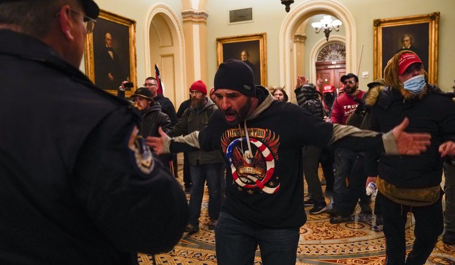 Rioters gesture to U.S. Capitol Police in the hallway outside of the Senate chamber at the Capitol in Washington, Wednesday, Jan. 6, 2021, near the Ohio Clock. (AP Photo/Manuel Balce Ceneta)  **FILE**