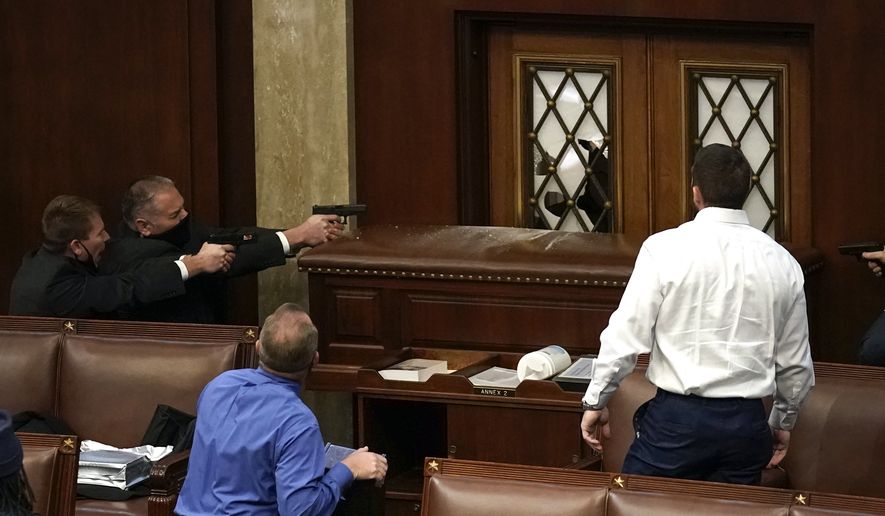 Police with guns drawn watch as rioters try to break into the House Chamber at the U.S. Capitol on Wednesday, Jan. 6, 2021, in Washington. (AP Photo/J. Scott Applewhite)
