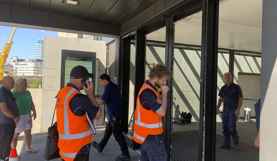 Crews at New Zealand&#39;s Parliament inspect the smashed front doors on Wednesday, Jan. 13, 2021, in Wellington, New Zealand. Police said a man armed with an axe smashed the glass doors but did not attempt to enter the building. (AP Photo/Nick Perry)