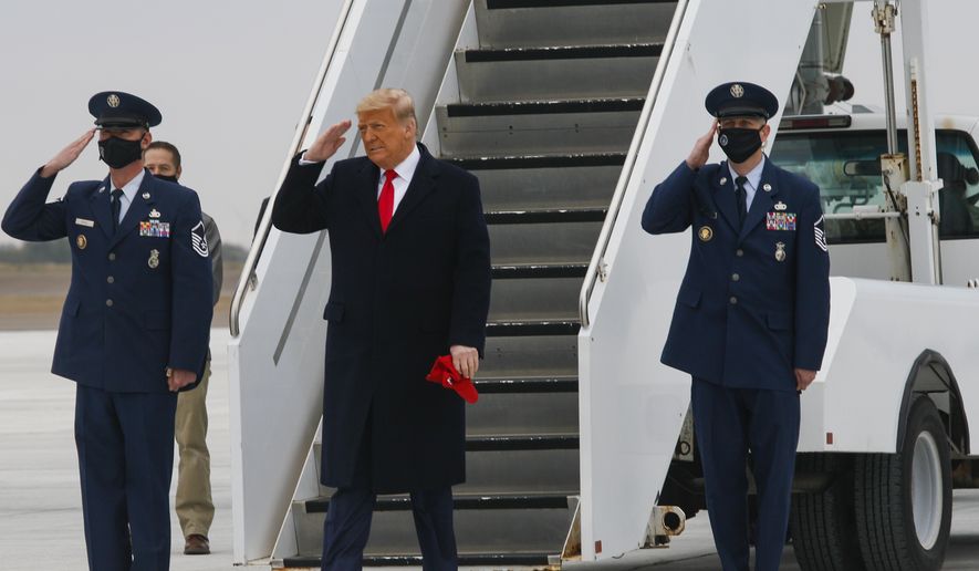President Donald J. Trump raises his hand in a salute Tuesday, Jan. 12, 2021, after arriving at Valley International Airport in Harlingen, Texas. (Denise Cathey/The Brownsville Herald via AP)