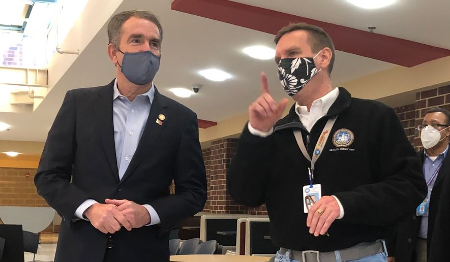 Dr. Stephen Haering (right), health director for the city of Alexandria, gives Virginia Gov. Ralph Northam a walkthrough of a coronavirus vaccine distribution center as the city began phase 1B of its rollout on Tuesday. (Gabriella Muñoz/The Washington Times)