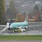 FILE - In this Wednesday, Nov. 18, 2020 file photo, workers stand near a Boeing 737 Max airplane parked at Renton Municipal Airport next to the Boeing assembly facility in Renton, Wash., where 737 Max airplanes are made. On Tuesday, Jan. 12, 2021, the company reported final 2020 numbers for airplane orders and deliveries, and they are down from 2019 even though the 737 Max is flying again. (AP Photo/Ted S. Warren)