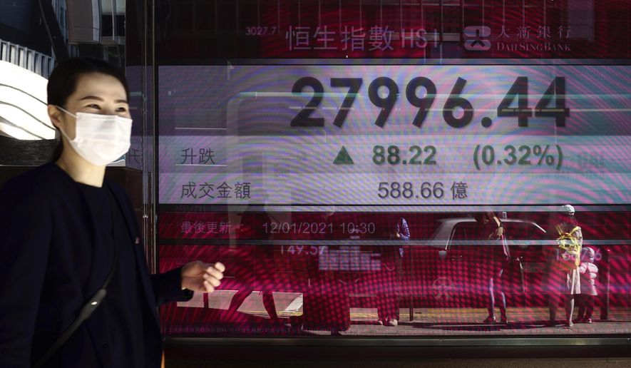A woman walks past a bank's electronic board showing the Hong Kong share index at Hong Kong Stock Exchange in Hong Kong Tuesday, Jan. 12, 2021. Asian stocks advanced Tuesday as investors watched for details of U.S. President-elect Joe Biden's promised economic stimulus plan. (AP Photo/Vincent Yu)