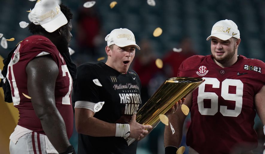 Alabama quarterback Mac Jones, middle, offensive linemen Alex Leatherwood, left, and Landon Dickerson, right, celebrate with the trophy, after their win against Ohio State in an NCAA College Football Playoff national championship game, Tuesday, Jan. 12, 2021, in Miami Gardens, Fla. Alabama won 52-24. (AP Photo/Chris O&#39;Meara)