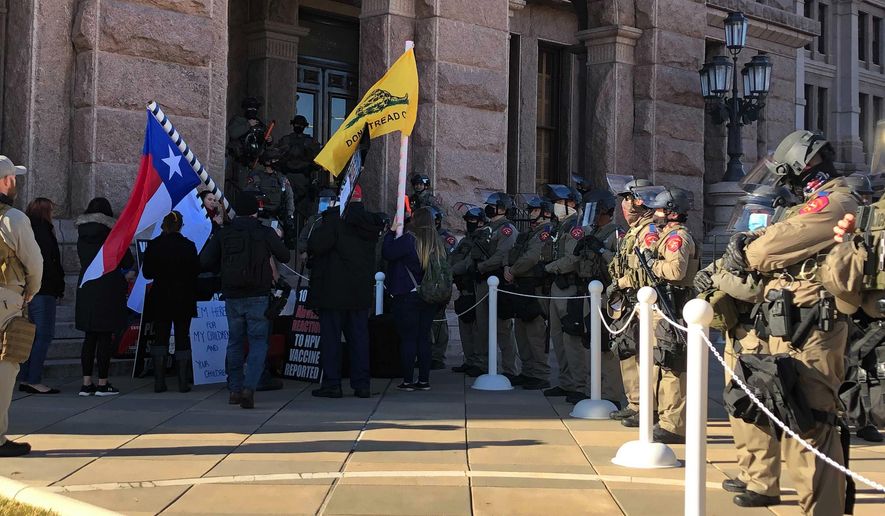 Protesters against COVID-19 vaccines face Texas state troopers wearing riot gear outside the Capitol in Austin, Texas, on Tuesday, Jan. 12, 2021, the opening day of the legislative session. The Texas Department of Public Safety has increased its presence at the state Capitol after last week's deadly attack on the U.S. Capitol by supporters of President Donald Trump. The FBI also has warned of plans for armed protests at all 50 state capitals and in Washington, D.C., in the days leading up to President-elect Joe Biden's inauguration. (AP Photo/Jim Vertuno)