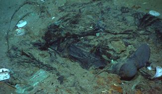 This 2004 photo provided by the Institute for Exploration, Center for Archaeological Oceanography/University of Rhode Island/NOAA Office of Ocean Exploration, shows the remains of a coat and boots in the mud on the sea bed near the Titanic&#39;s stern. Fallout from the coronavirus pandemic is threatening a company’s plans to retrieve and exhibit the radio that had broadcast distress calls from the sinking vessel, according to a court filing made by the firm on Monday, Jan. 11, 2021.   (Institute for Exploration, Center for Archaeological Oceanography/University of Rhode Island/NOAA Office of Ocean Exploration)