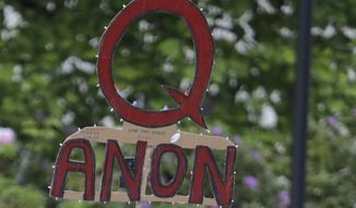 In this May 14, 2020, file photo, a person carries a sign supporting QAnon during a protest rally in Olympia, Wash, USA. (AP Photo/Ted S. Warren, File)