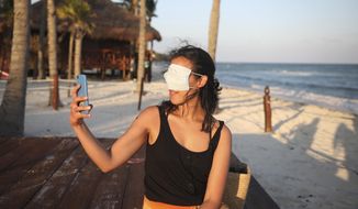 Mexico City resident Romina Montoya takes a playful selfie wearing a protective face mask over her eyes and nose, in Playa del Carmen, Quintana Roo state, Mexico, Wednesday, Jan. 6, 2021. Concern is spreading that the critical winter holiday tourism success could be fleeting because it came as COVID-19 infections in both Mexico and the United States were reaching new heights. (AP Photo/Emilio Espejel) **FILE**