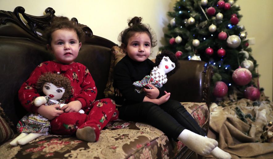 Sama Chlawuit, left, and her sister Sima-Rita, whose family home had the windows blown out during August&#39;s massive explosion in Beirut, hold their dolls at their grandfather&#39;s home, in Beirut, Lebanon, Tuesday, Dec. 29, 2020. After the explosion, painter Yolande Labaki made 100 dolls for children affected by the destruction. (AP Photo/Hussein Malla)