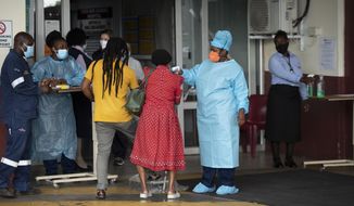 A health worker checks the temperature of an elderly patient at the emergency entrance of the Steve Biko Academic Hospital in Pretoria, South Africa, Monday, Jan. 11, 2021, which is battling an ever-increasing number of COVID-19 patients. (AP Photo/Themba Hadebe)