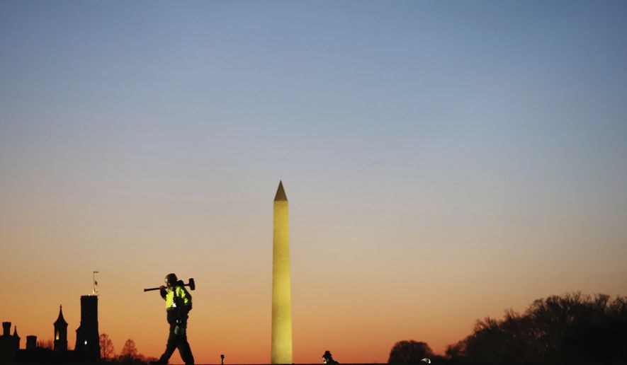 A construction worker carries a hammer on his shoulder on Wednesday, Jan. 13, 2021 at the National Mall in Washington, as a stage is prepared for the 2021 Democrat Joe Biden&#39;s presidential inauguration. (AP Photo/Shafkat Anowar)