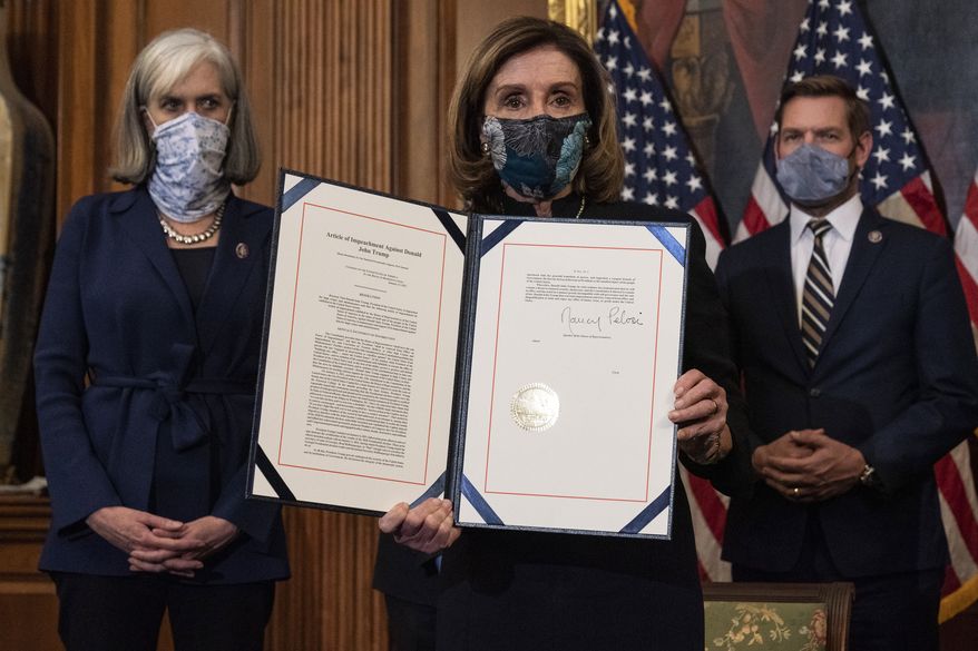 House Speaker Nancy Pelosi of Calif., holds the article of impeachment against President Donald Trump after signing it, in an engrossment ceremony before transmission to the Senate for trial on Capitol Hill, in Washington, Wednesday, Jan. 13, 2021. (AP Photo/Alex Brandon)