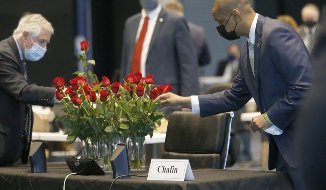 Members of the Senate, including Sen. John Edwards, D-Roanoke, left, Sen. David Suetterlein, R-Roanoke, center and Lt. Gov. Justin Fairfax, right, placed roses on the desk of the late Sen. Ben Chafin, R-Russell, on opening day of the General Assembly inside the Science Museum in Richmond, Va., Wednesday, Jan. 13, 2021. Chafin died on Jan. 1 due to complications related to the coronavirus. (Bob Brown/Richmond Times-Dispatch via AP)