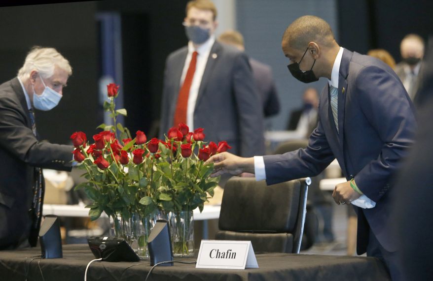 Members of the Senate, including Sen. John Edwards, D-Roanoke, left, Sen. David Suetterlein, R-Roanoke, center and Lt. Gov. Justin Fairfax, right, placed roses on the desk of the late Sen. Ben Chafin, R-Russell, on opening day of the General Assembly inside the Science Museum in Richmond, Va., Wednesday, Jan. 13, 2021. Chafin died on Jan. 1 due to complications related to the coronavirus. (Bob Brown/Richmond Times-Dispatch via AP)