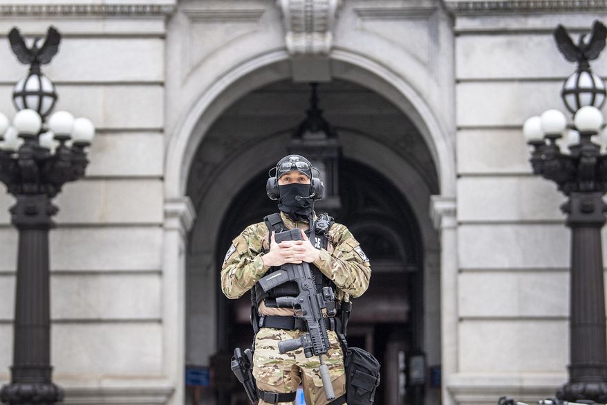 A member of the Pennsylvania Capitol Police guards the entrance to the Pennsylvania Capitol Complex in Harrisburg, Pa. Wednesday, Jan. 13, 2021. State capitols across the country are under heightened security after the siege of the U.S. Capitol last week.  (Jose F. Moreno/The Philadelphia Inquirer via AP)