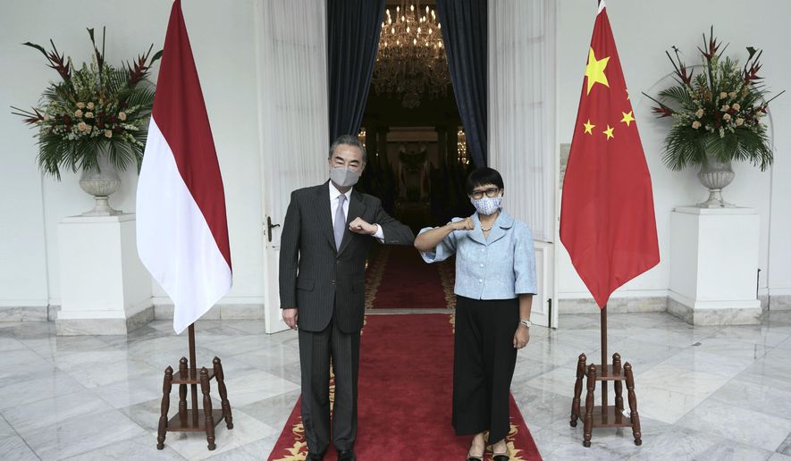 In this photo released by Indonesian Foreign Ministry, Chinese Foreign Minister Wang Yi, left, poses for photographers with his Indonesian counterpart Retno Marsudi during their meeting in Jakarta, Indonesia, Wednesday, Jan. 13, 2021. Wang pledged that China will help Indonesia defeat the coronavirus, including providing vaccines and the strengthen economic cooperation with Indonesia in addition to strengthening cooperation in the health sector in overcoming the COVID-19 pandemic. (Indonesian Foreign Ministry via AP)