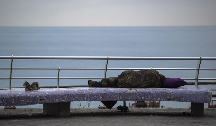 FILE - In this, July 19, 2020 file photo, a homeless woman sleeps on a bench on the Mediterranean Sea corniche in Beirut, Lebanon. The World Bank has approved a $246 million loan to Lebanon to provide emergency cash assistance to nearly 800,000 Lebanese reeling under the country’s compounded economic and health crises. The World Bank said in a statement late Tuesday, Jan. 12, 2021, that the loan would also support the development of a national social safety net in Lebanon. (AP Photo/Hassan Ammar, File)