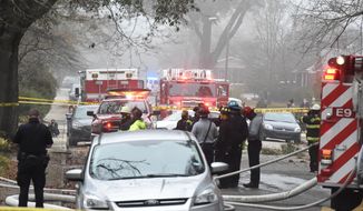 Officials clean up the scene following a small plane crash during dense fog in a residential neighborhood on Wednesday, Jan. 13, 2021, in Columbia, S.C. Authorities say the woman in the home was able to get out safely and have not given information on the condition of anyone aboard the plane. (AP Photo/Meg Kinnard)