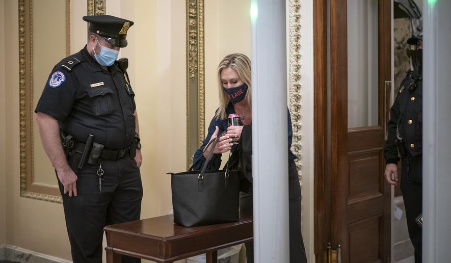 Rep. Marjorie Taylor Greene, R-Ga., an ally of President Donald Trump, passes through a metal detector before entering the House chamber, a new security measure put into place after a mob stormed the Capitol, in Washington, Tuesday, Jan. 12, 2021. (AP Photo/J. Scott Applewhite)