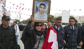 FILE - In this April 9, 2012 file photo, a Tunisian woman holds a poster of her martyr son named Helmi Manaai, written under the photo, during a protest in Tunis. Since winning a parliamentary seat in 2019, Tunisian lawmaker Abir Moussi has become one of the country’s most popular, and most controversial, politicians, riding a wave of nostalgia for a more stable and prosperous time, just as Tunisia marks 10 years since protesters overthrew autocratic former President Zine El Abidine Ben Ali. Since 2011, Tunisia has been plagued by sinking wages, growing joblessness and worsening public services. Unemployment has risen amid the coronavirus pandemic from 15% to 18%. Attempts to migrate to Europe by sea have soared. (AP Photo/Amine Landoulsi, File)