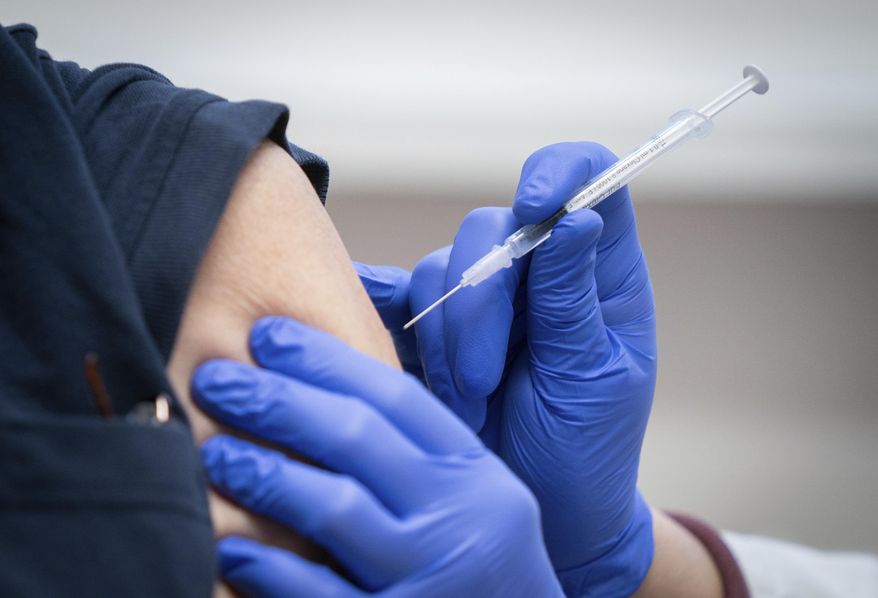 Nurse gives an injection with the Biontech/Pfizer vaccine against Covid-19 disease to an employee at the Bethel Hospital in Berlin, Germany, Wednesday, Jan. 13, 2021. A total of 66 employees will be vaccinated at the hospital with the first the Biontech/Pfizer vaccine. (Kay Nietfeld/dpa via AP)