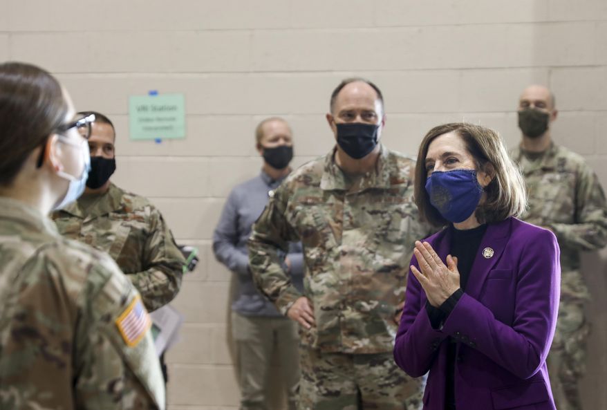 Oregon Gov. Kate Brown visits with National Guard members at the Marion County and Salem Health COVID-19 vaccination clinic on Wednesday, Jan. 13, 2021 at the Oregon State Fairgrounds in Salem, Ore.(Abigail Dollins/Statesman-Journal via AP, Pool)