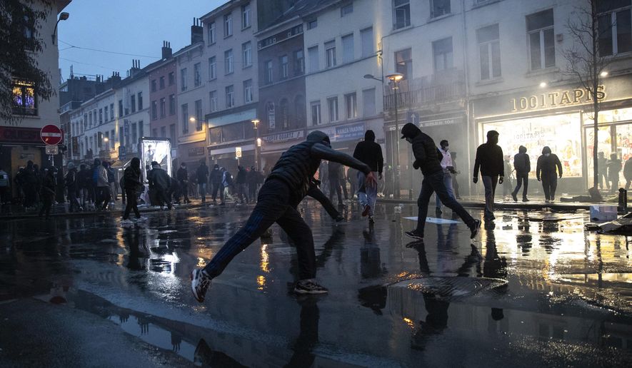Rioters throw stones in the Belgium capital, Brussels, Wednesday, Jan. 13, 2021, at the end of a protest asking for authorities to shed light on the circumstances surrounding the death of a 23-year-old Black man who was detained by police last week in Brussels. The demonstration in downtown Brussels was largely peaceful but was marred by incidents sparked by rioters who threw projectiles at police forces and set fires before it was dispersed. (AP Photo/Francisco Seco)