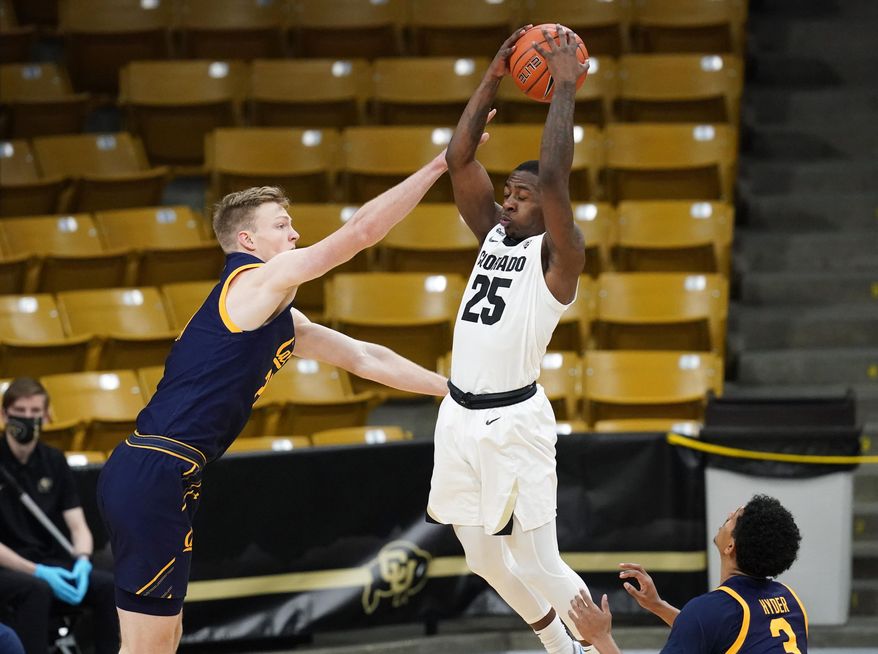 Colorado guard McKinley Wright IV, center, pulls in a rebound between California guards Ryan Betley, left, and Jarred Hyder in the first half of an NCAA college basketball game Thursday, Jan. 14, 2021, in Boulder, Colo. (AP Photo/David Zalubowski)