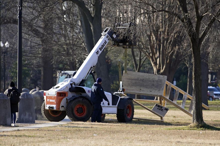 In this Jan. 7, 2021, file photo, crew remove a scaffolding near the U.S. Capitol that had a noose hanging from it the day before in Washington. Both within and outside the walls of the Capitol, banners and symbols of white supremacy and anti-government extremism were displayed as an insurrectionist mob swarmed the U.S. Capitol. (AP Photo/Matt Slocum, File)