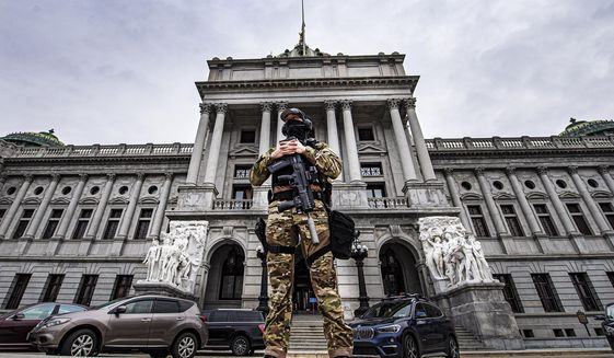 A member of the Pennsylvania Capitol Police stands guard at the entrance to the Pennsylvania Capitol Complex in Harrisburg, Pa., Wednesday, Jan. 13, 2021. State capitols across the country are under heightened security after the siege of the U.S. Capitol last week.  (Jose F. Moreno/The Philadelphia Inquirer via AP)