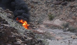FILE - In this Saturday, Feb. 10, 2018, file photo, a survivor, lower right, walks away from the scene of a deadly tour helicopter crash along the jagged rocks of the Grand Canyon in Arizona. The pilot of the helicopter that crashed in the Grand Canyon in 2018, killing five British tourists, says he lost control of the aircraft after a &amp;quot;violent gust of wind&amp;quot; sent it spinning. The National Transportation Safety Board released its final report Thursday, Jan. 14, 2021, that said tailwinds, potential downdrafts and turbulence were the probable cause of the loss of control and tail-rotor effectiveness. (Teddy Fujimoto via AP, File)