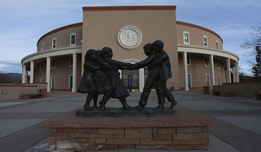 The sculpture "Tug 'O War" sculpture by artist Glenna Goodacre sits at the entrance to the New Mexico State capitol building on Wednesday, Jan. 13, 2021, in Santa Fe, New Mexico. The sculpture now sits inside a fences erected following the Jan. 6 riot in Washington, D.C., after safety concerns for the upcoming legislative session. (AP Photo/Cedar Attanasio)