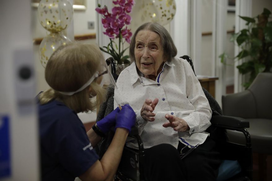 Care home resident Joan Potts, aged 102, is seen through a viewing screen installed for residents to safely receive visits from family members, as she speaks to Dr. Jane Allen before receiving her first dose of the Oxford/AstraZeneca COVID-19 vaccine at the Wimbledon Beaumont Care Home, run by Barchester, in south west London, Wednesday, Jan. 13, 2021, during England's third national lockdown since the coronavirus outbreak began. (AP Photo/Matt Dunham)