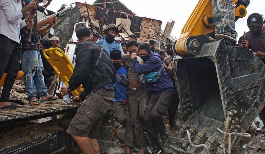 Rescuers assist a survivor pulled out from the ruin of a government building collapsed during an earthquake in Mamuju, West Sulawesi, Indonesia, Friday, Jan. 15, 2021. A strong, shallow earthquake shook Indonesia&#x27;s Sulawesi island just after midnight Friday, toppling homes and buildings, triggering landslides and killing a number of people. (AP Photo/Azhari Surahman)