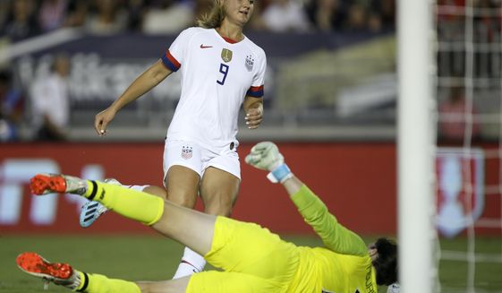 FILE - In this Aug. 3, 2019, file photo, United States midfielder Lindsey Horan, top, scores against Ireland goalkeeper Marie Hourihan during the first half of an international friendly soccer match in Pasadena, Calif. Horan described herself as miserable when she caught COVID-19 late last year.The 26-year-old midfielder was set to accompany the U.S. national team to the Netherlands for their final match of the year when U.S. Soccer announced her diagnosis on Nov. 18. (AP Photo/Alex Gallardo, File)