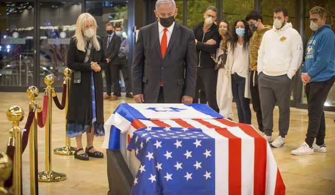 Israeli Prime Minister Benjamin Netanyahu stands before the casket of Sheldon Adelson upon arrival to Ben Gurion Airport, near the city of Lod, Israel, Thursday, Jan. 14, 2021. Adelson&#x27;s family, including his wife, Miriam, at left, are present. Adelson, the billionaire mogul and power broker who built a casino empire spanning from Las Vegas to China and became a singular force in domestic and international politics has died after a long illness, his wife said Tuesday, Jan. 12, 2021. (Ami Shooman, Israel Hayom/ Pool Photo via AP)
