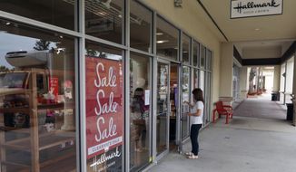 A sale sign is displayed near the entrance of a Hallmark store Tuesday, Jan. 12, 2021, in Orlando, Fla.  Retail sales fell for a third straight month, as a surge in virus cases kept people away from stores and restaurants during the holiday shopping season.     The report released Friday is yet another sign that the pandemic is slowing the U.S. economy. Last month, the country lost jobs for the first time since the spring.(AP Photo/John Raoux)