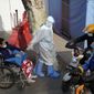 A medical worker in protector overall escorts a patient in wheelchair from the fever screening department of the Tongji Hospital which was at the frontline of the China&#39;s fight against the coronavirus in Wuhan in central China&#39;s Hubei province on Friday, Jan. 15, 2021. The WHO team of international researchers that arrived in the central Chinese city of Wuhan on Thursday hopes to find clues to the origin of the COVID-19 pandemic. (AP Photo/Ng Han Guan)