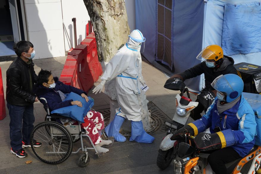 A medical worker in protector overall escorts a patient in wheelchair from the fever screening department of the Tongji Hospital which was at the frontline of the China&#x27;s fight against the coronavirus in Wuhan in central China&#x27;s Hubei province on Friday, Jan. 15, 2021. The WHO team of international researchers that arrived in the central Chinese city of Wuhan on Thursday hopes to find clues to the origin of the COVID-19 pandemic. (AP Photo/Ng Han Guan)