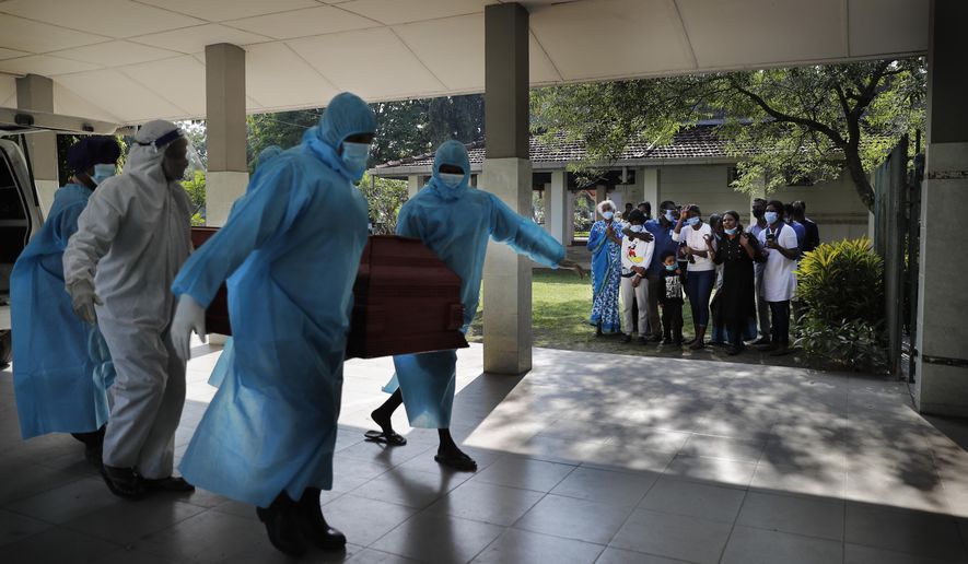A Sri Lankan Christian family grieves as municipal cemetery workers carry the body of their family member who died of COVID-19 for cremation in Colombo, Sri Lanka, Friday, Dec. 11, 2020. (AP Photo/Eranga Jayawardena)