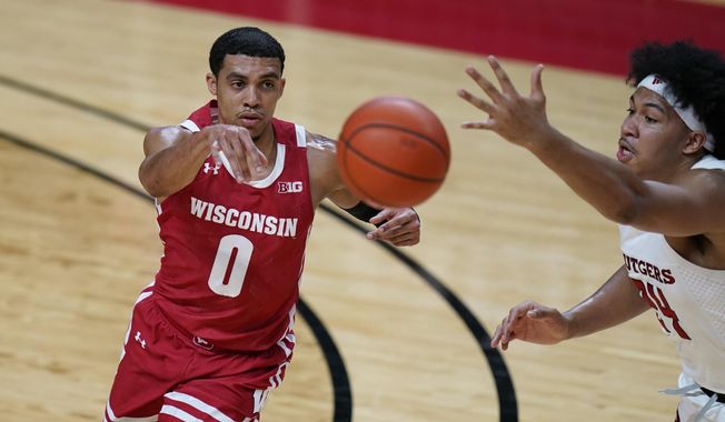 Wisconsin&#x27;s D&#x27;Mitrik Trice, left, passes the ball past Rutgers&#x27; Ron Harper Jr. during the first half of an NCAA college basketball game Friday, Jan. 15, 2021, in Piscataway, N.J. (AP Photo/Seth Wenig)