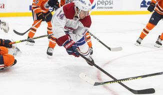 Montreal Canadiens&#39; Nick Suzuki (14) dives for the puck against the Edmonton Oilers during first-period NHL hockey game action in Edmonton, Alberta, Saturday, Jan. 16, 2021. (Jason Franson/The Canadian Press via AP)