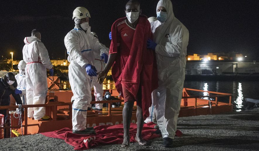 A man is helped off a rescue ship in the port of Arguineguin, Gran Canaria island, Spain, Saturday Jan. 16, 2021. The Spanish rescue ship rescued a boat 160 kilometres south of Gran Canaria with 11 men, 20 women and 3 children on board in very poor condition. (AP Photo/Javier Bauluz)