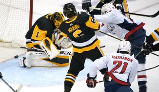 Washington Capitals&#39; Nic Dowd (26) puts the puck behind Pittsburgh Penguins goaltender Casey DeSmith (1) for a goal during with Penguins&#39; John Marino (6) defending during the first period of an NHL hockey game in Pittsburgh, Sunday, Jan. 17, 2021. (AP Photo/Gene J. Puskar)